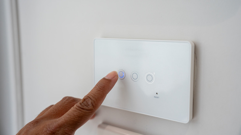 Person pressing smart light switch panel