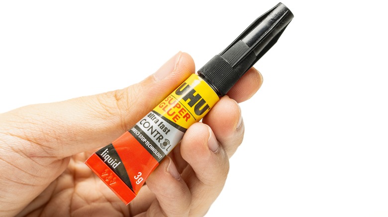 A hand holding UHU Super Glue