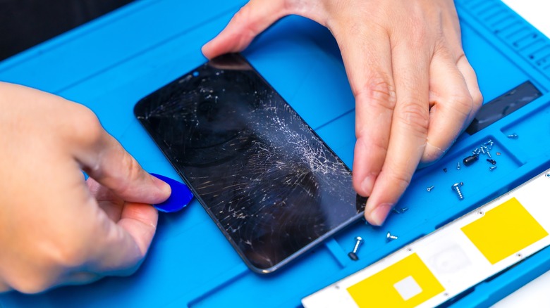 Close-up top view of a technician removing a smartphone screen