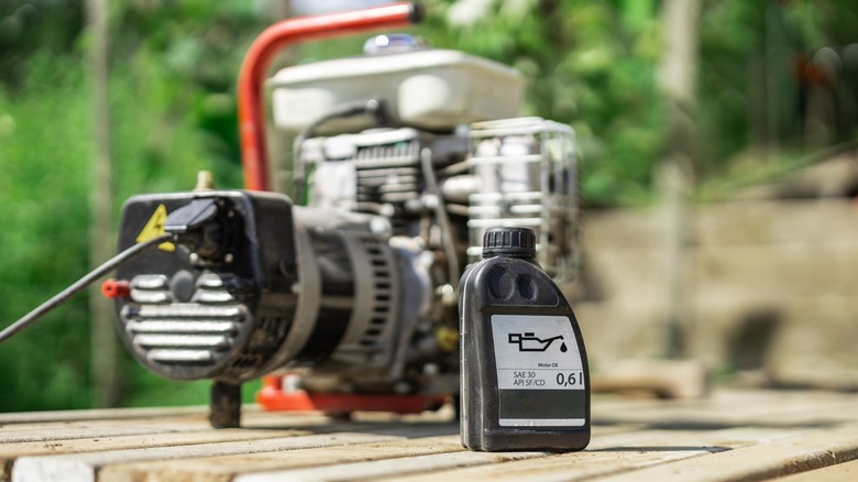 An engine oil container in front of a small portable generator.
