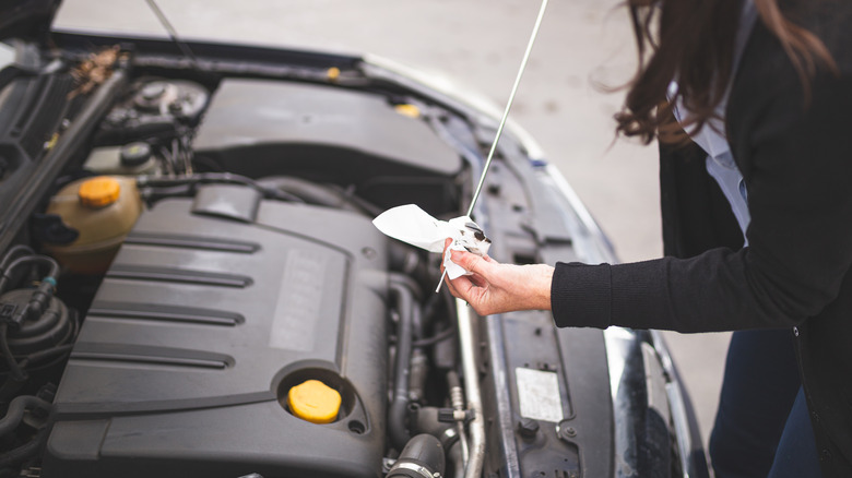 Woman wiping oil dipstick after checking oil levels