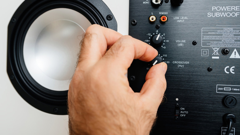 Person adjusting crossover setting on speakers