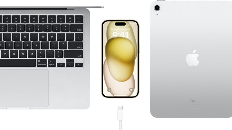 iPhone 15 between MacBook and iPad, with USB-C cable beneath it