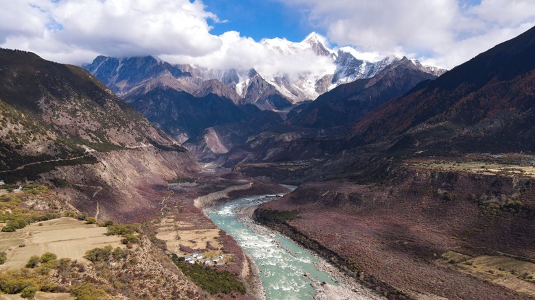 A mountain valley with a river in the foreground and Namcha Barwa mountain in the distance
