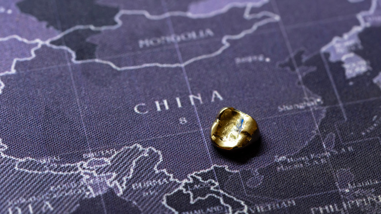China on a world map with a small gold nugget on top