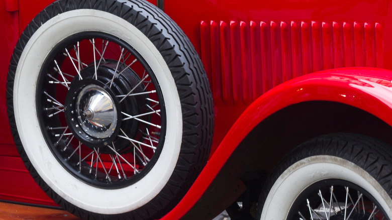 Close-up of antique whitewall-tire equipped car, showing front-right tire and side-mounted spare tire