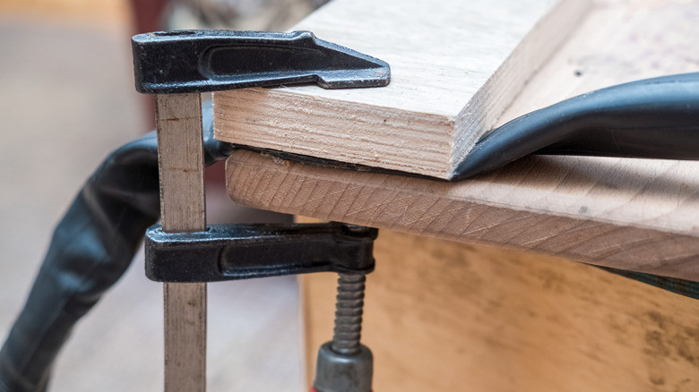 Pieces of wood and hosing held together with a black bar clamp