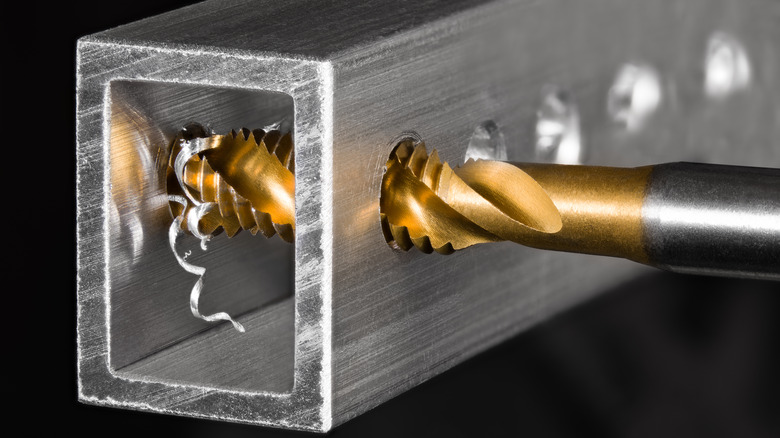 A drill bit going through metal