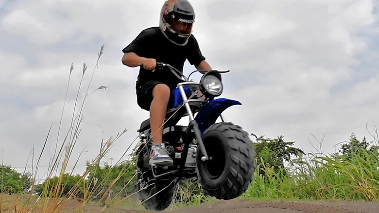 A rider tackling a dirt track jump aboard a Massimo Mini Bike 200S.