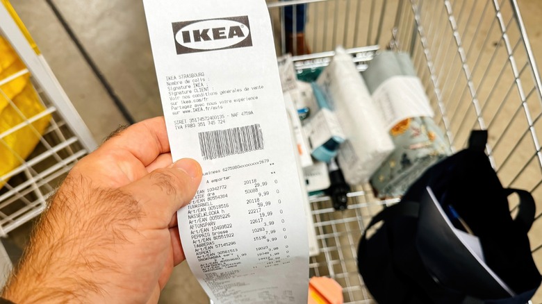 A person carrying an Ikea receipt with some of the bought items sitting in the background