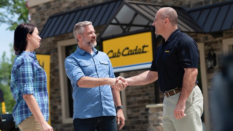 People smiling and shaking hands at the Cub Cadet dealer.