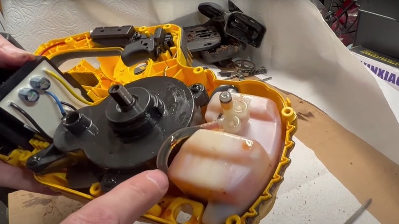 Disassembled Dewalt chainsaw showing oil spill on components