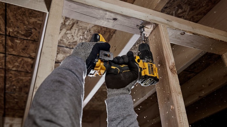 Person using a DeWalt DCD799 drill to chip wood overhead.