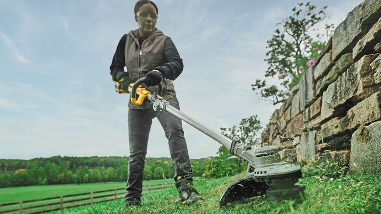 A woman trimming a yard with a weed eater