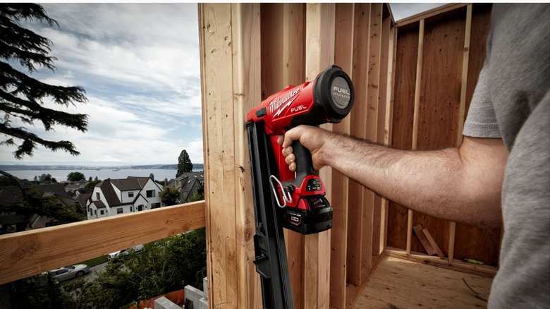 A man holding a Milwaukee framing nailer