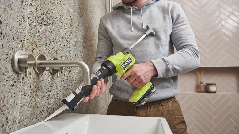 A person sealing gaps in their sink with the Ryobi caulk gun