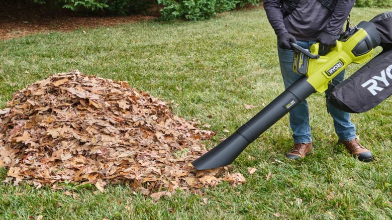 A worker using a 40V Ryobi blower and vacuum to suck up leaves.