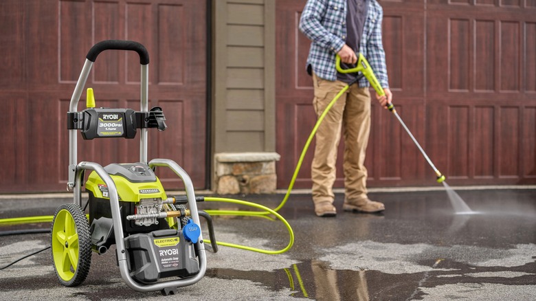 A man cleaning a floor with a Ryobi pressure washer