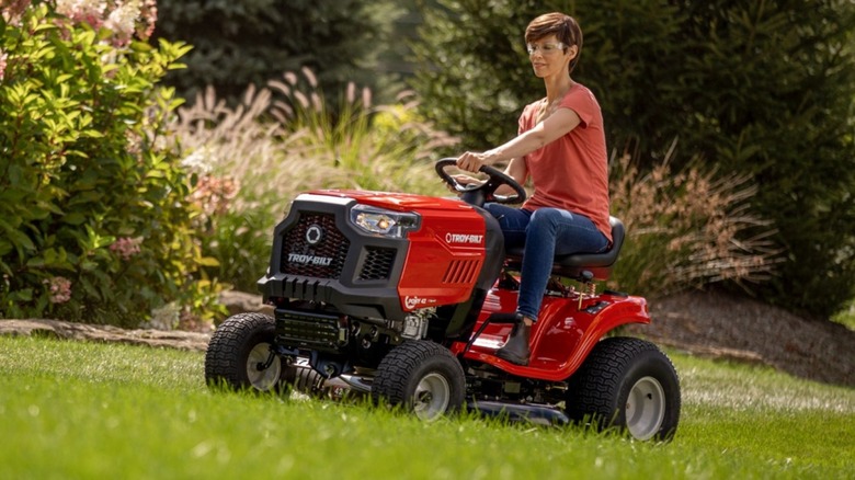 A person mowing the grass aboard a Troy-Bilt riding lawn mower.