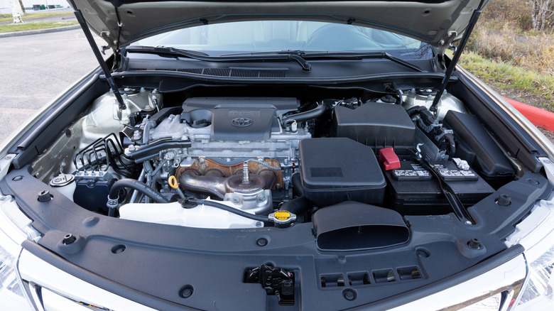 A white Toyota Camry with its hood opened, showcasing the Toyota V6 engine.