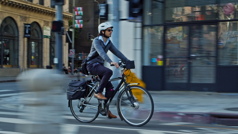 A man wearing a helmet riding an e-bike in a city