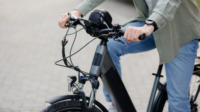 A man in jeans and a great shirt riding an electric bike