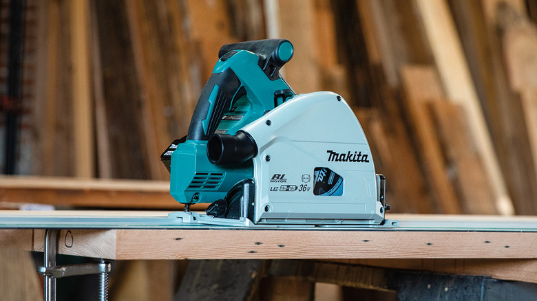 a cordless Makita track saw sitting on a slab of wood