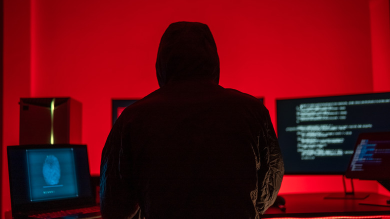 The silhouette of cyber hacker is busy at work over a laptop.