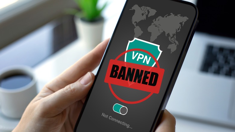 Person holding phone with VPN banned on screen