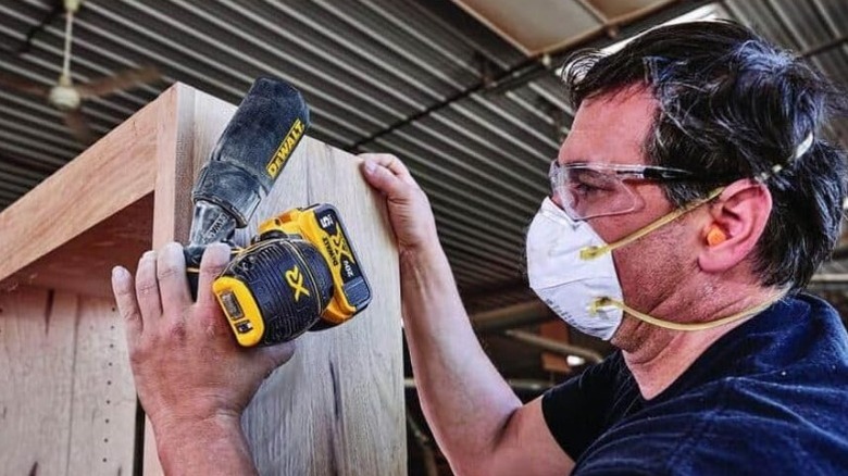 Person using DeWalt sander on bookshelf