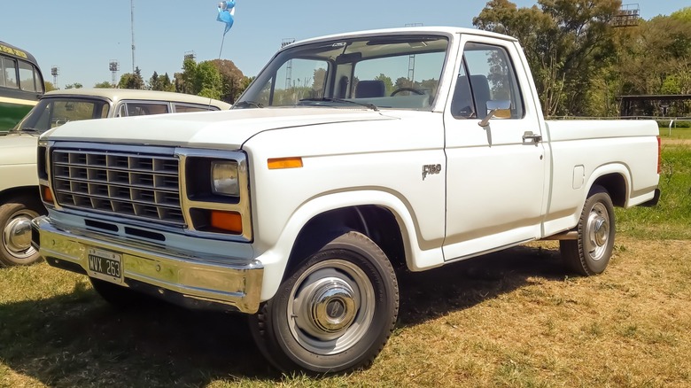 A white 1980s Ford F-150 parked on grass