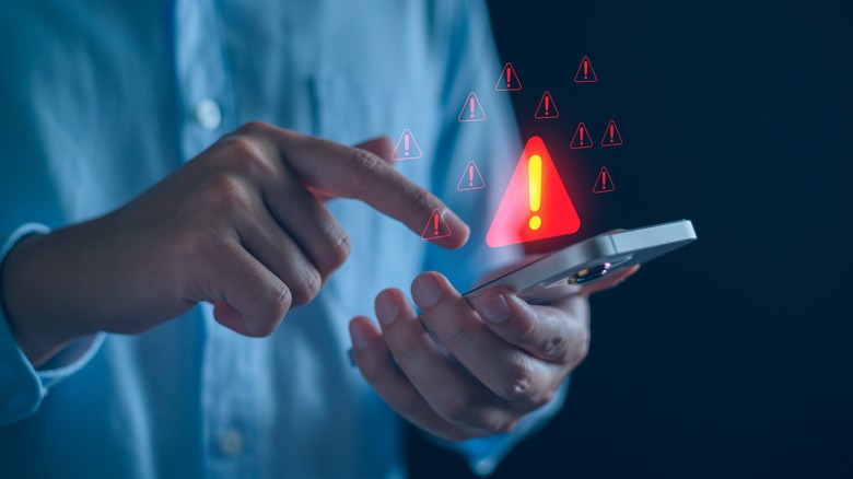 Person touching smartphone with warning sign graphics