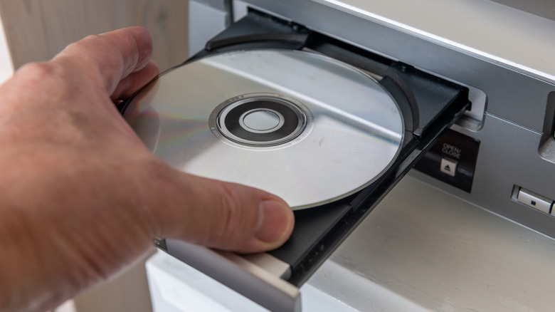 A person putting a disc into a disc drive.
