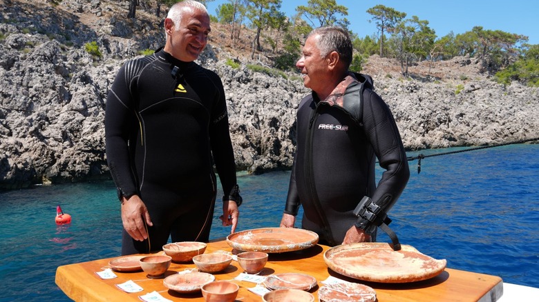 Two divers on the surface examining pottery found in an ancient shipwreck off the coast of Turkey