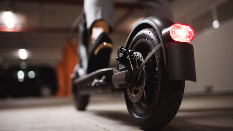 Close up on woman legs and feet standing on the electric kick scooter