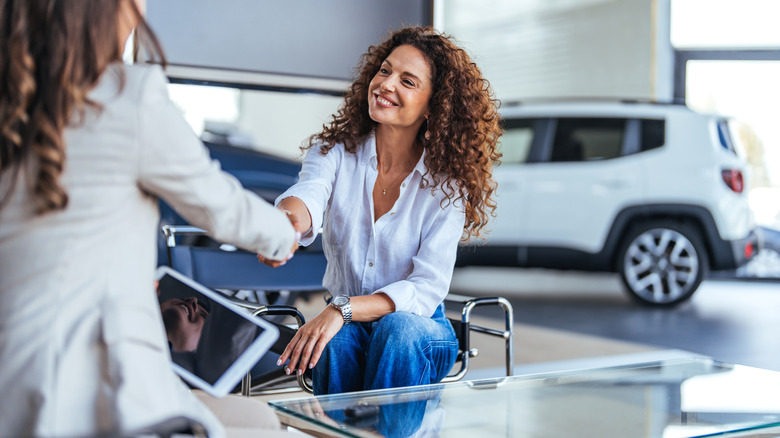 Woman buying new car with a sales representative