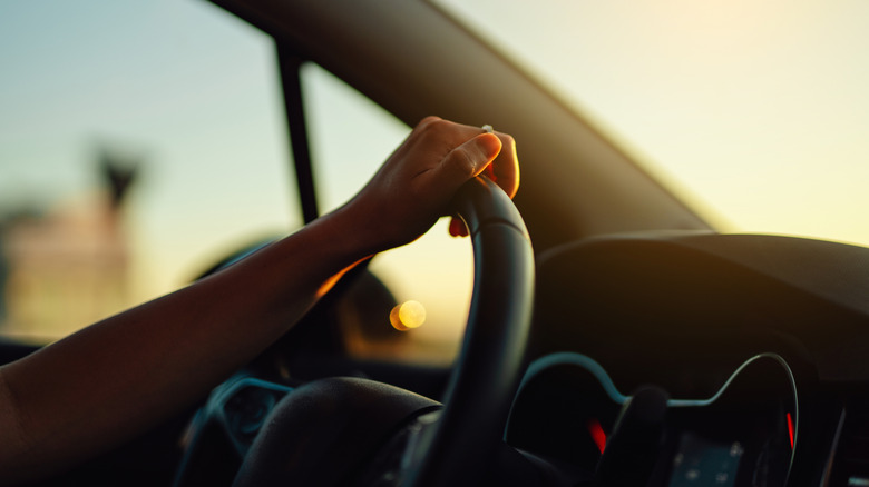 Close-up of arm of a woman holding on to steering wheel while driving