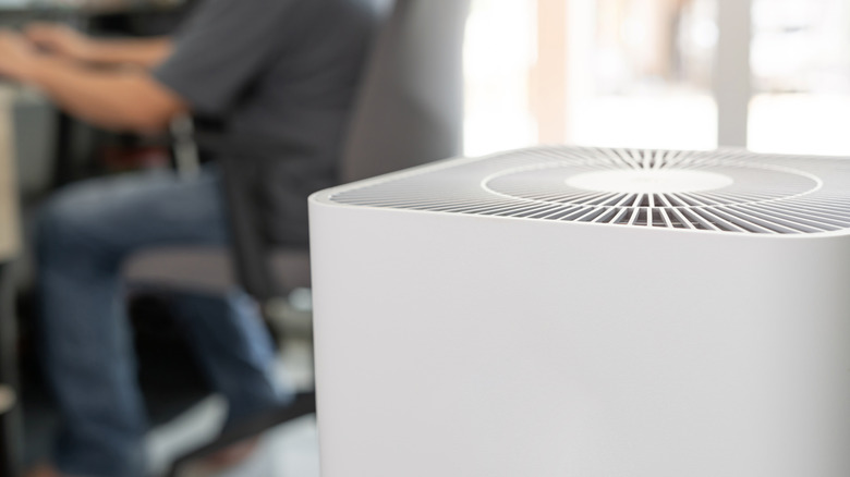 Man working on desk with air purifier in foreground