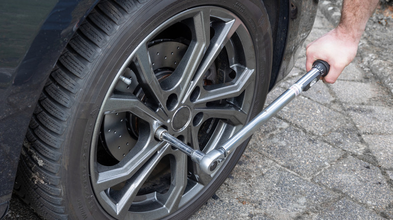 Man using socket wrench with extension on tire