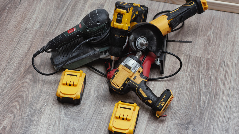 Collection of power tools and batteries piled up on a floor