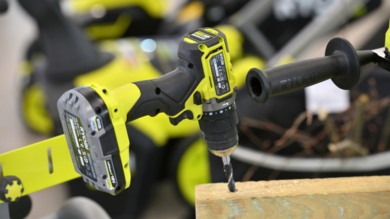 A Ryobi drill on display attached to a wooden plank, Ryobi battery installed