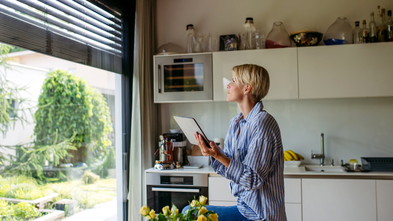 A woman with short hair closing metal blinds in her smart home