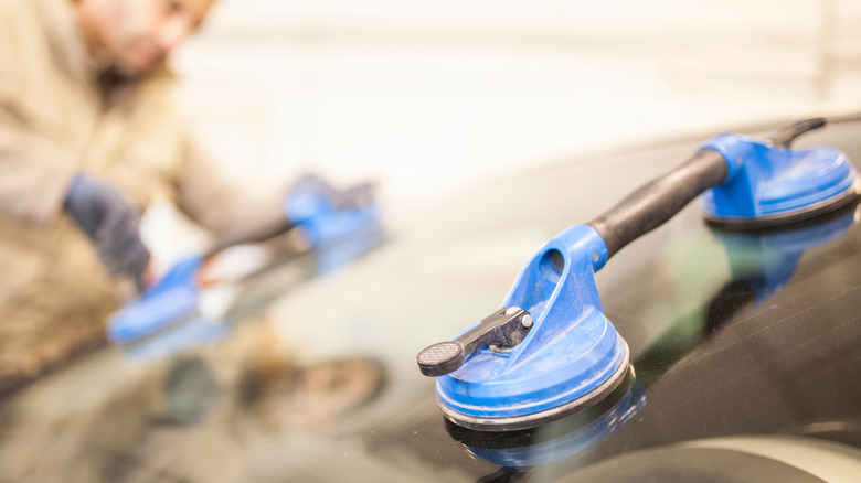 A mechanic using suction cup dent pullers on a car body panel