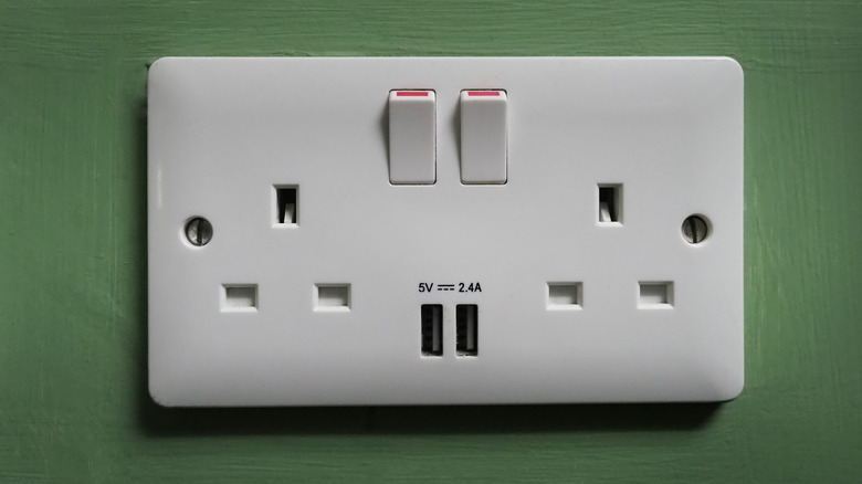 Electrical outlet with USB ports on a green wall