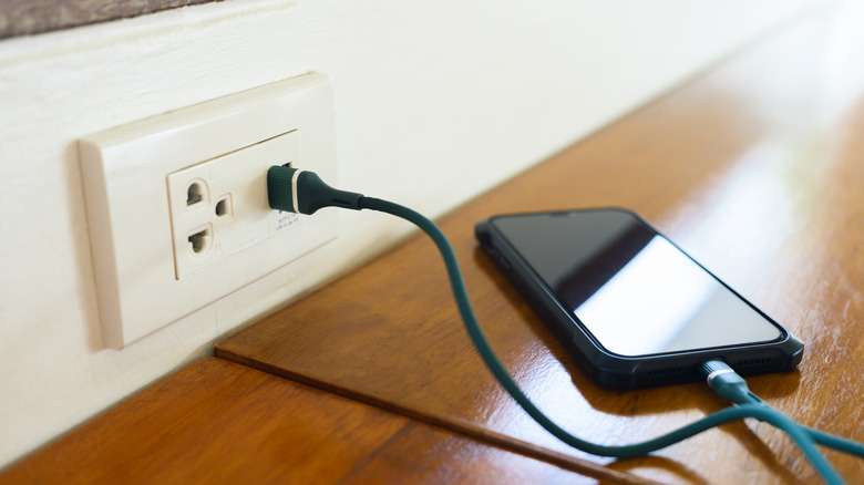 Smartphone plugged into outlet with USB charging ports