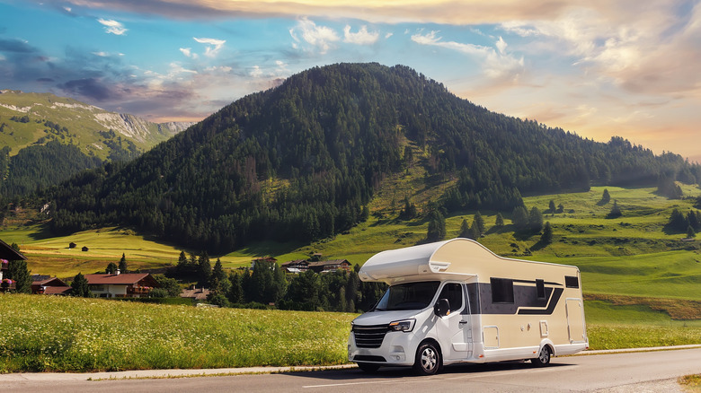 A motorhome on a road with mountain peaks in the background