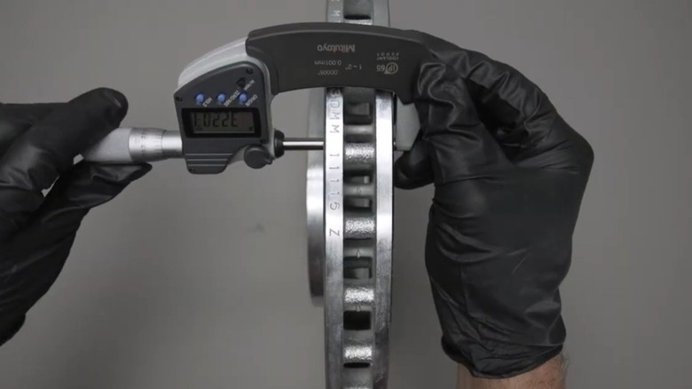 A technician measuring the thickness of a brake rotor.