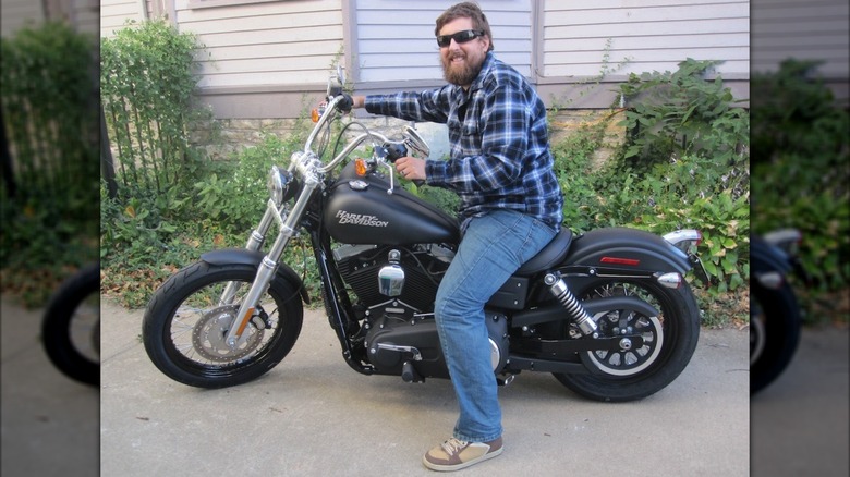 Man in blue plaid shirt sitting on a 2011 Harley-Davidson Street Bob.