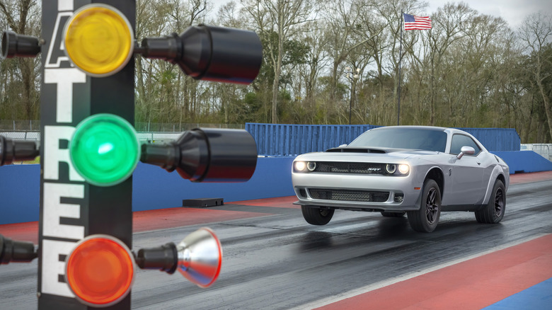 Dodge Demon 170 launching at drag strip with staging tree in foreground, front-left view