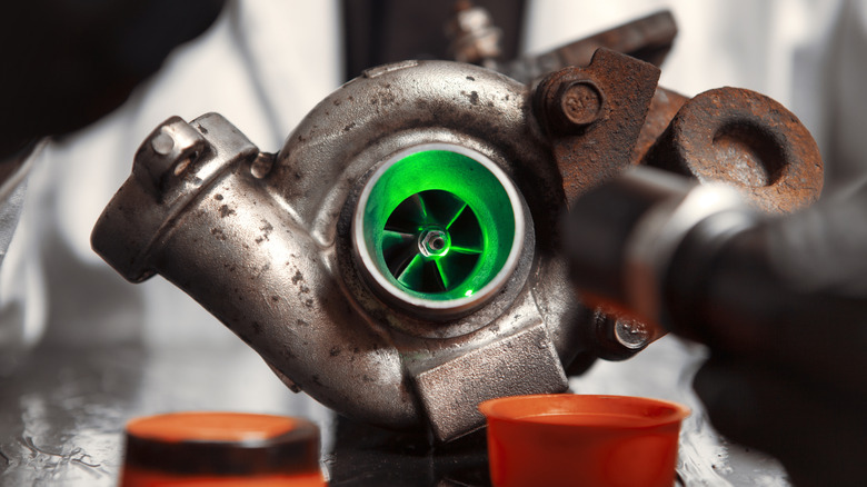 A turbocharger on a workbench, green LED illuminating the insides